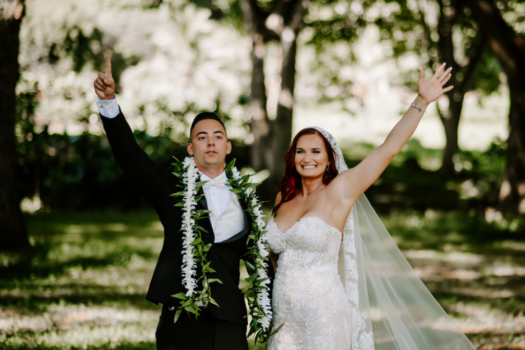 bride and groom throwing their hands up in excitement
