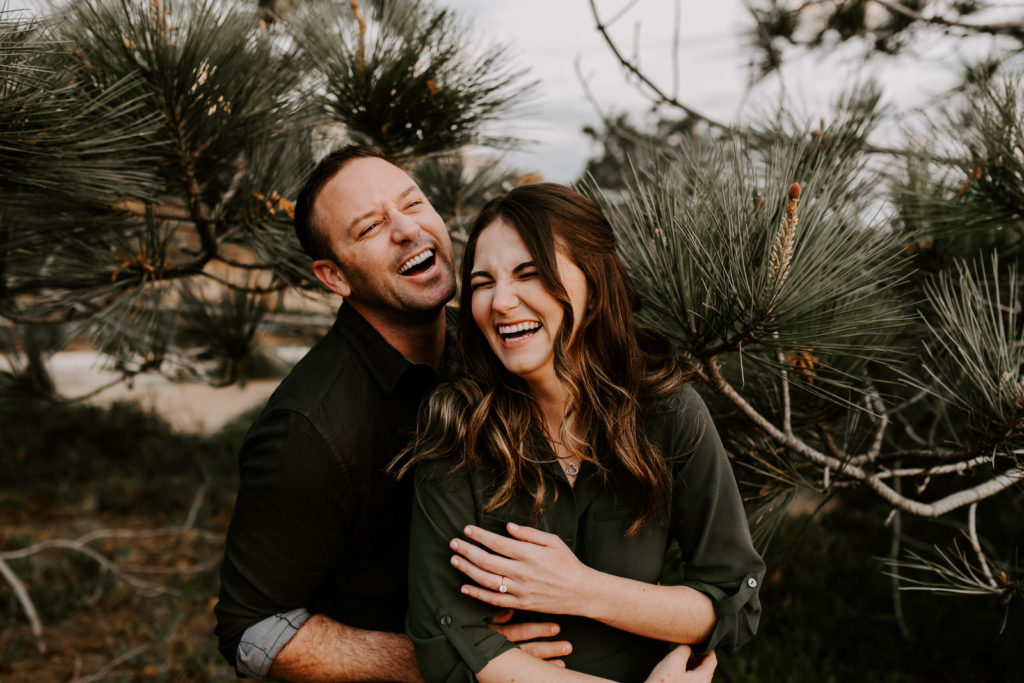 Couple laughing with Torrey Pine trees behind them