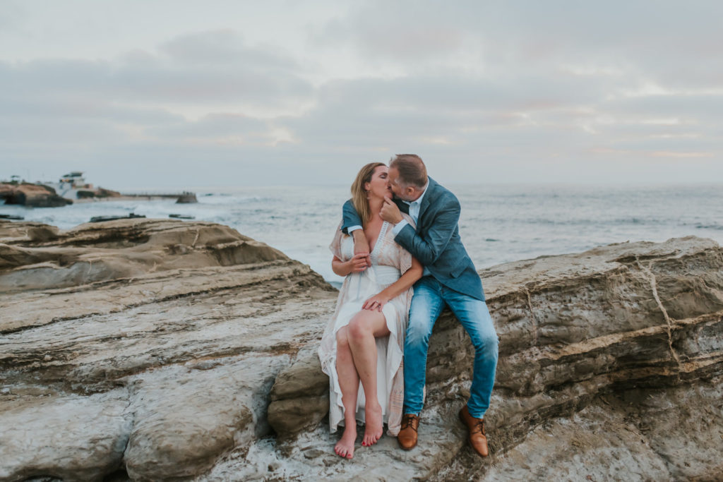 couple sitting on the La Jolla cliffs kissing