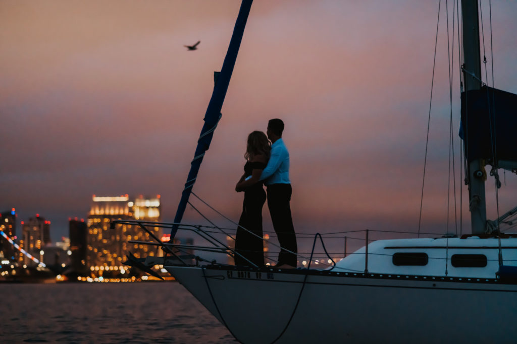 couple standing on boat with city in the back