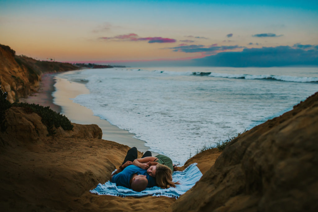 couple cuddling on a picnic blanket on the cliffs