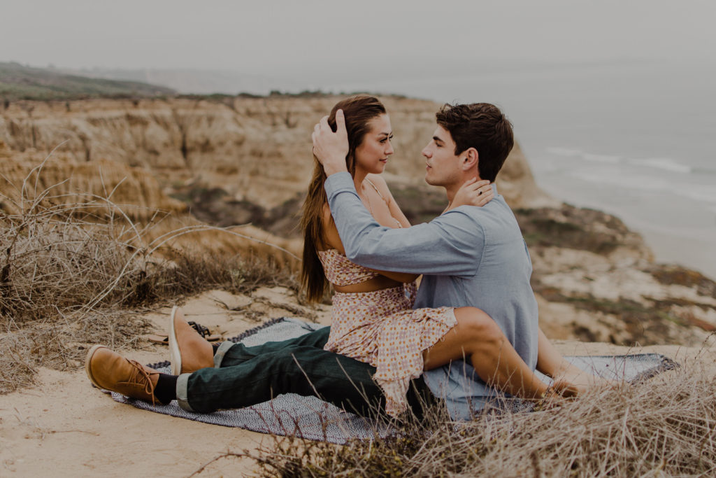 Couple sitting on a picnic blanket on a cliff at Torrey Pines