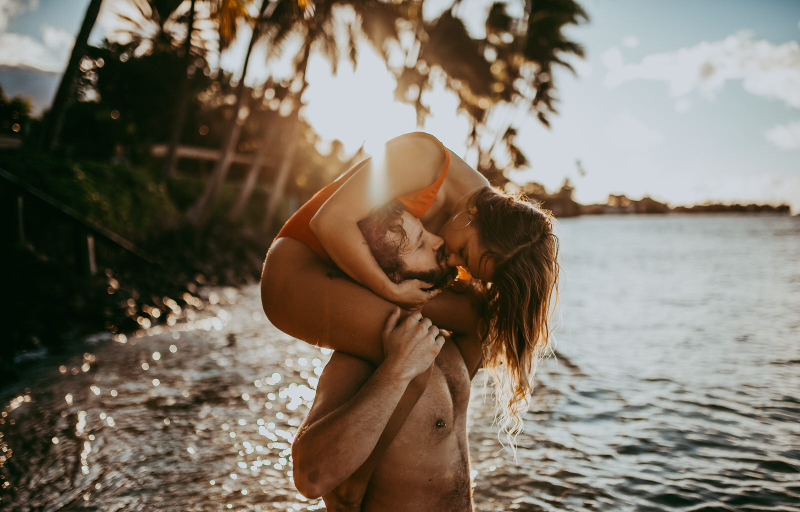 woman on mans shoulder at the beach in maui kissing