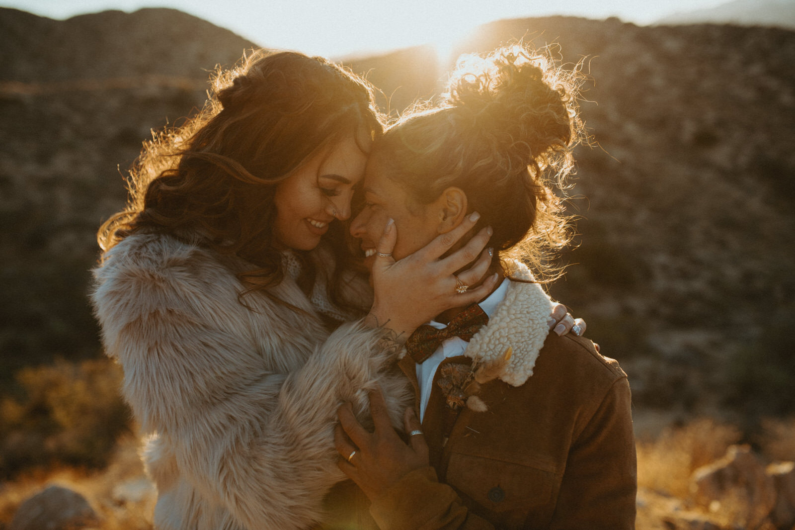 Two brides kissing in front of the sunset at their wedding in Joshua Tree
